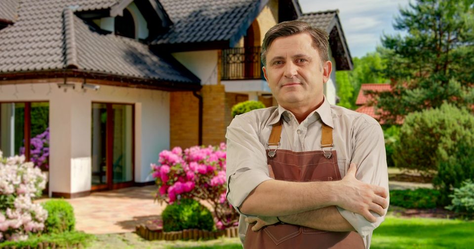 Gardener in front of a house with roses