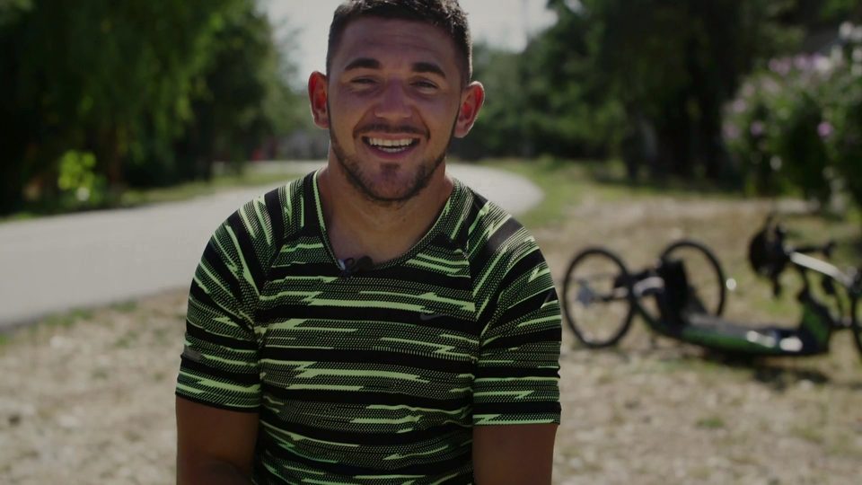 Florin Mihuț smiling, with his handbike behind him